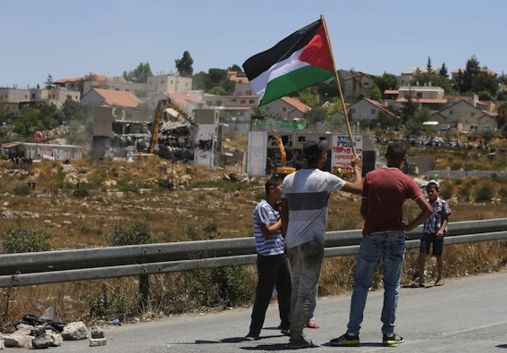Varios palestinos observan los trabajos para derribar los dos edificios cuya demolición ha ordenado el Supremo israelí. (Abbas MOMANI/AFP PHOTO)