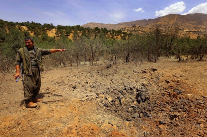 Un miembro del PKK señala al cráter provocado por un proyectil lanzado por Turquía. (Safin HAMED/AFP PHOTO)
