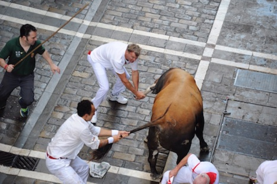 Dos corredores sujetan al toro para apartarlo de los corredores caídos. (Jon URBE/ARGAZKI PRESS)