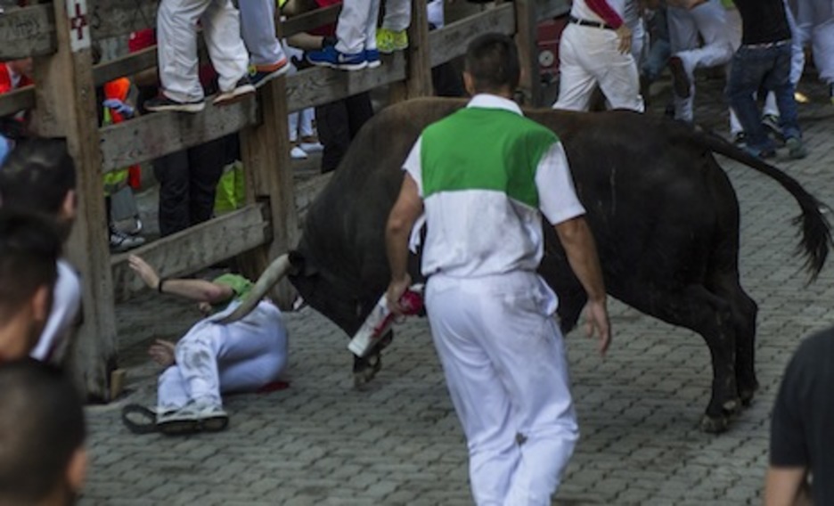 Un toro suelto se lanza por un corredor caído en el callejón. (Jagoba MANTEROLA/ARGAZKI PRESS)