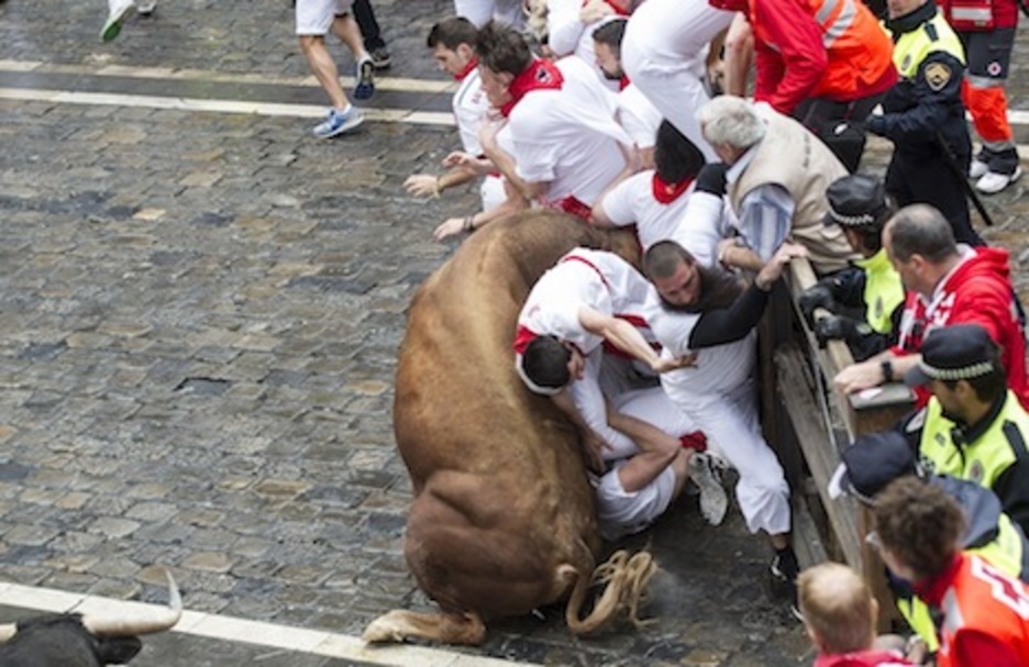 El toro colorado se lanza contra un grupo de corredores que está en el vallado. (Jagoba MANTEROLA/ARGAZKI PRESS)