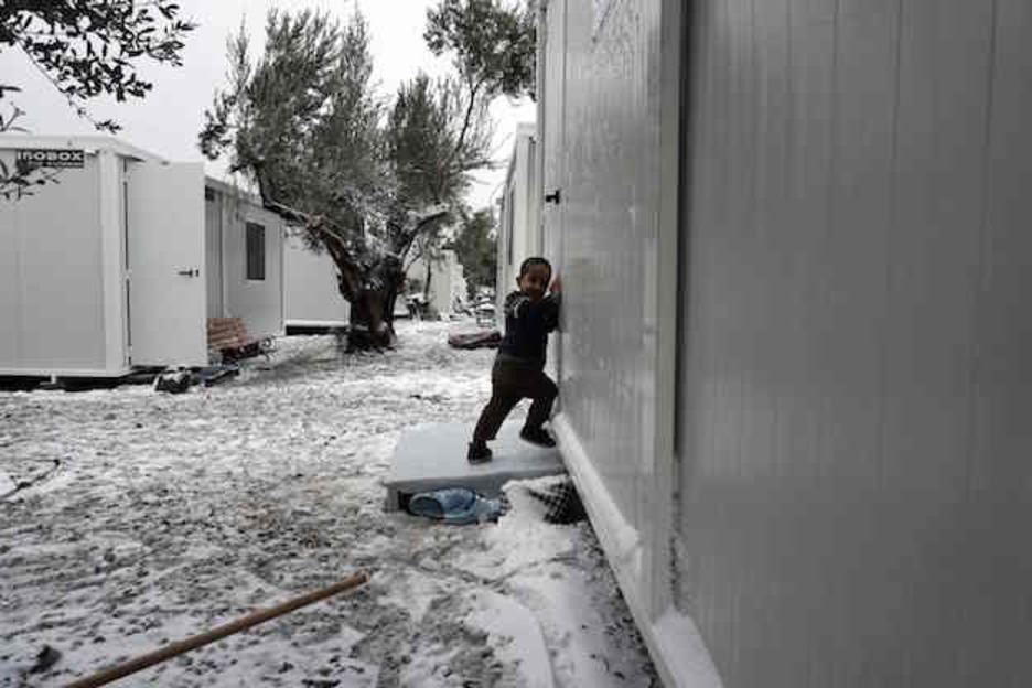 Un niño, a la puerta de un barracón en Lesbos. (AFP PHOTO / STR)