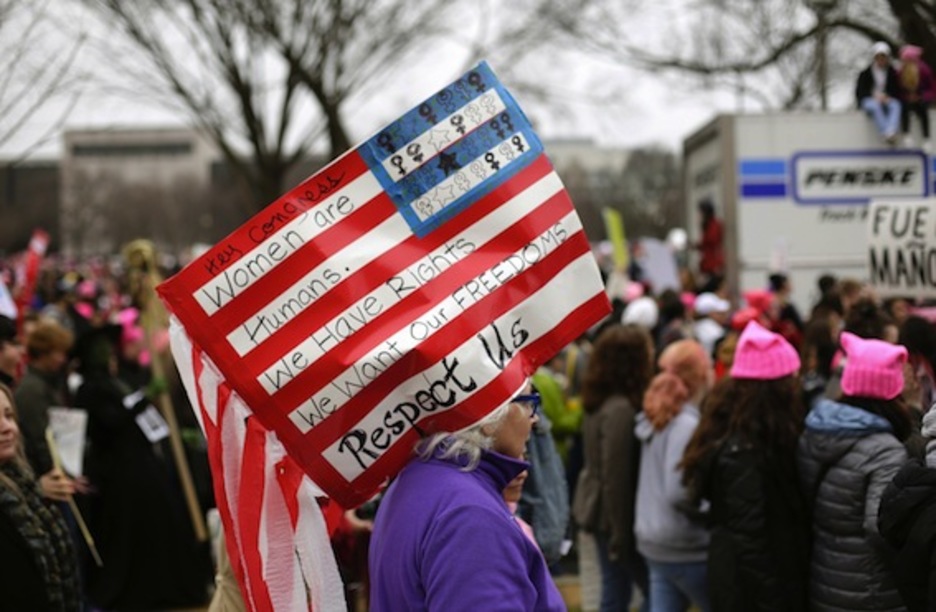 Una mujer porta en la cabeza una bandera de EEUU en la que apela a respetar los derechos de las mujeres. (Joshua LOTT/AFP)
