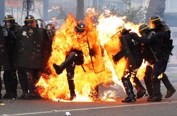 Policías entre las llamas de algún artefacto incendiario. (ZAKARIA ABDELKAFI / AFP)