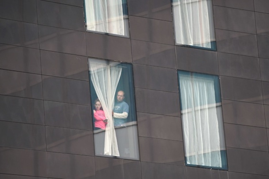 Dos personas miran desde la ventana de un hotel cercano al Manchester Arena. (Oli SCARFF/AFP)
