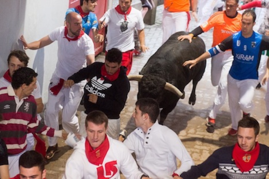 Varios corredores ponen la mano sobre el toro que iba en cabeza. (Iñigo URIZ/ARGAZKI PRESS)