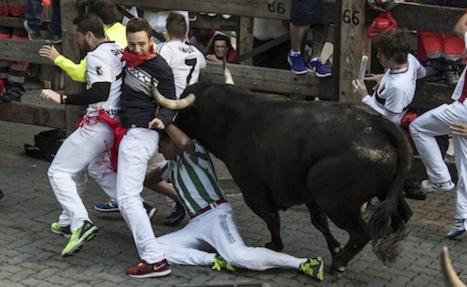 El primer corredor cae al suelo, mientras el toro alcanza al grupo delantero de corredores. (Jagoba MANTEROLA/ARGAZKI PRESS)