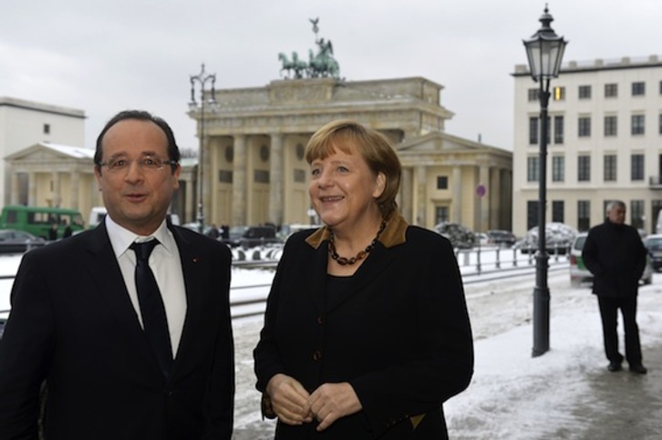 François Hollande charla con Angela Merkel con la Puerta de Brandenburgo al fondo. (Odd ANDERSEN/AFP PHOTO)