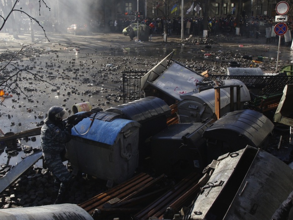 Un policía dispara protegido por contenedores de basura. (Anatolii STEPANOV /AFP PHOTO)