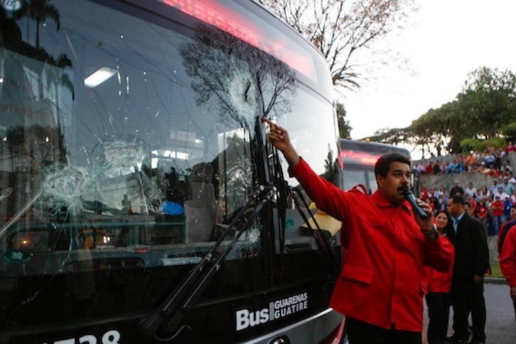 El presidente de Venezuela, Nicolás Maduro, muestra un autobús atacado en las protestas. (AFP PHOTO)