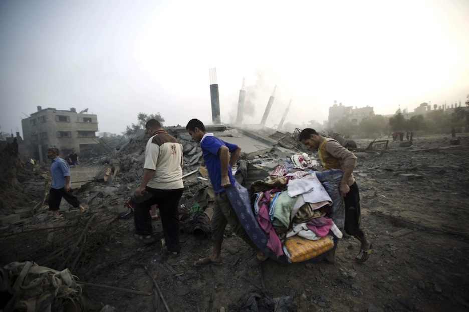 Varios palestinos recogen los pocos enseres que les han quedado después de que su casa haya sido destruida. (Mahmud HAMS/AFP)