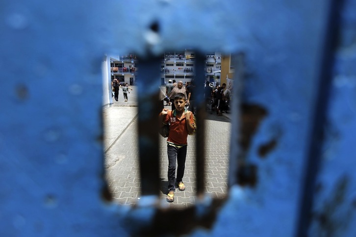 Imagen de un niño tras la puerta de una escuela de la ONU en Beit Lahia. (Mohammed ABED/AFP)
