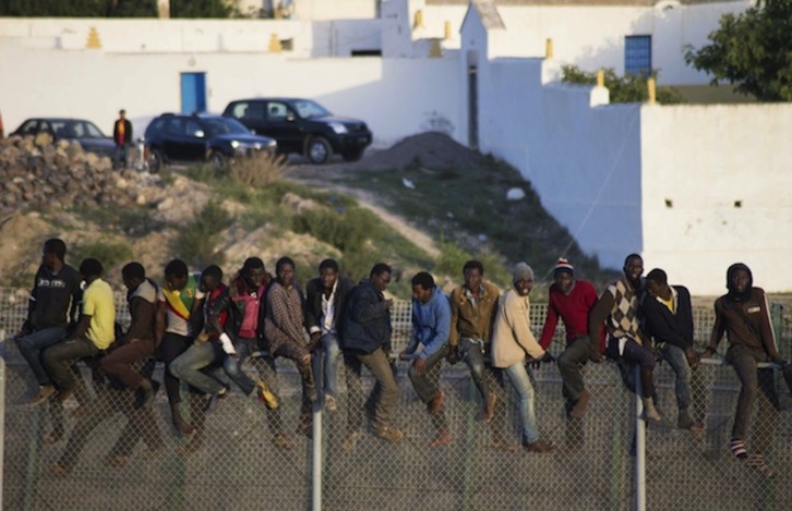 Inmigrantes encaramados a la valla de Melilla. (Blasco AVELLANEDA / AFP)
