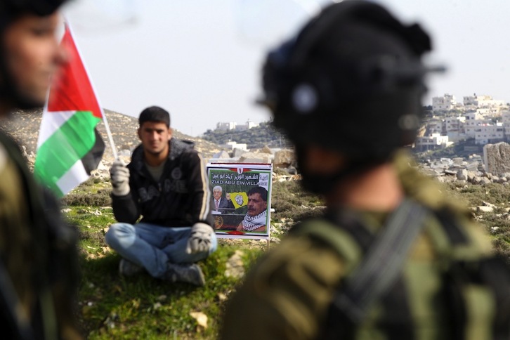 Un joven palestino frente a dos soldados israelís. (Hazem BADER / AFP)