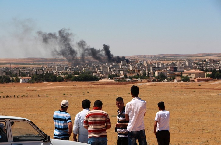 Un grupo de kurdos observa desde la frontera turca la columna de humo que emerge de Kobane. (AFP)