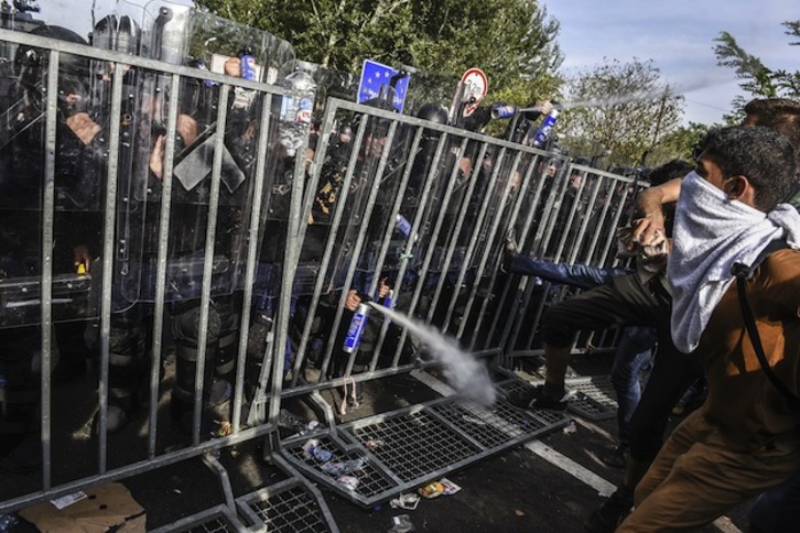 Policías y refugiados en la frontera entre Hungría y Serbia. (Armend NIMANI / AFP) 