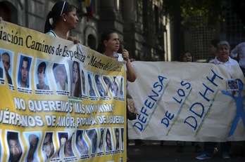 Representantes de las Madres de la Candelaria de Colombia sostienen una pancarta con fotos de desaparecidos durante el conflicto armado. (Raúl ARBOLEDA/AFP) 