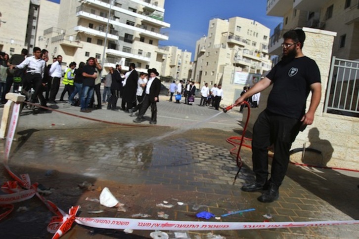 Un hombre quita con una manguera la sangre del lugar donde los palestinos han recibido los tiros. (Gil COHEN-MAGEN/AFP PHOTO)