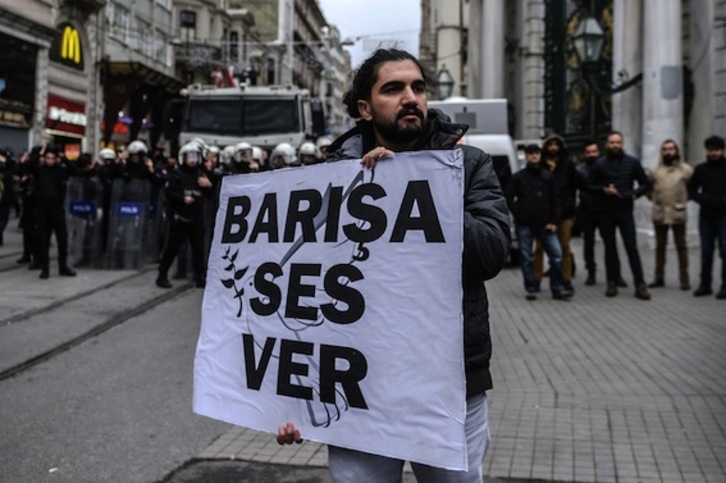 Un artista local muestra un cartel por la paz durante una protesta en Estambul. (Ozan KOSE/AFP)