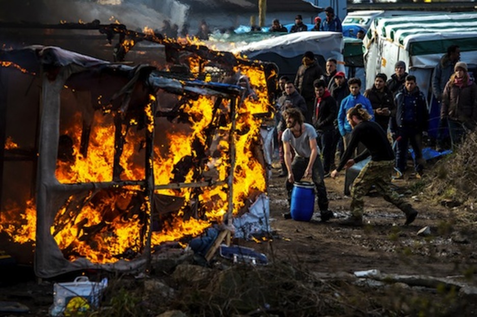 Voluntarios tratan de apagar un fuego en el campamento. (Philippe HUGUEN/AFP) 