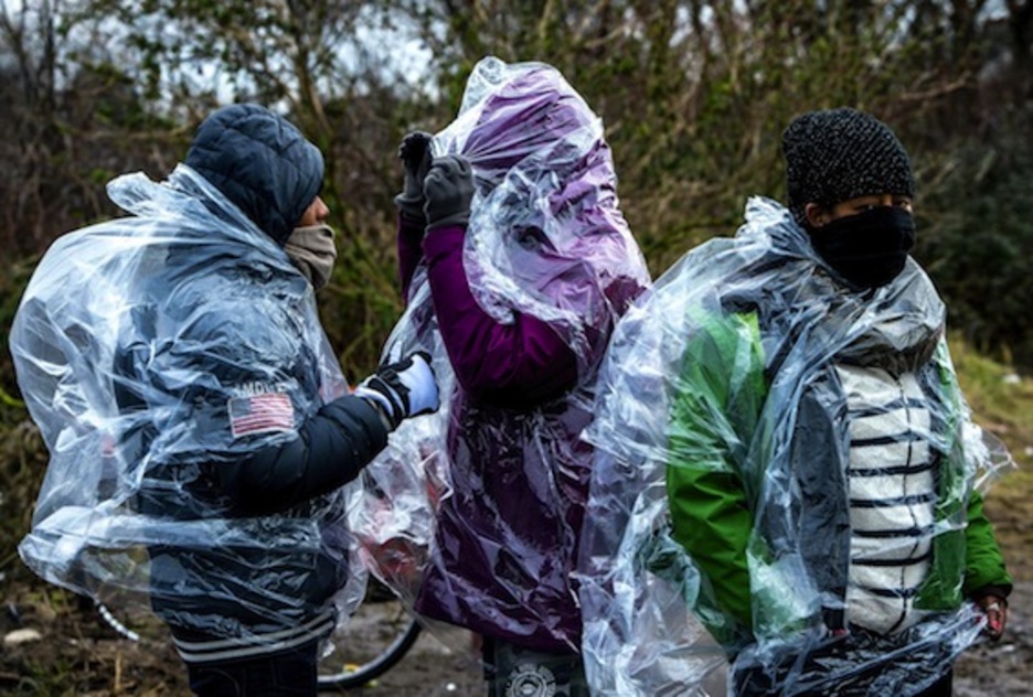 Tres refugiados eritreos se protegen de la lluvia. (Philippe HUGUEN/AFP) 