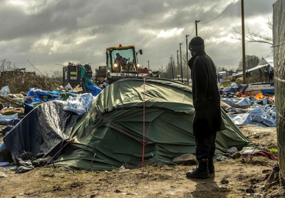 Un hombre mira a una excavadora que trabaja en el desmantelamiento del campamento.  (Philippe HUGUEN/AFP) 