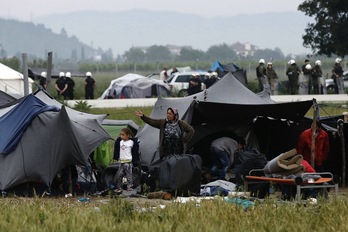 Una familia de refugiados espera fuera de su tienda durante el desalojo. (AFP)