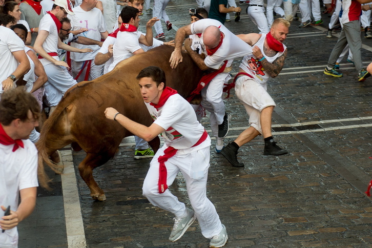 Momento en el que el toro colorado coge a uno de los corredores. (Iñigo URIZ/ARGAZKI PRESS)