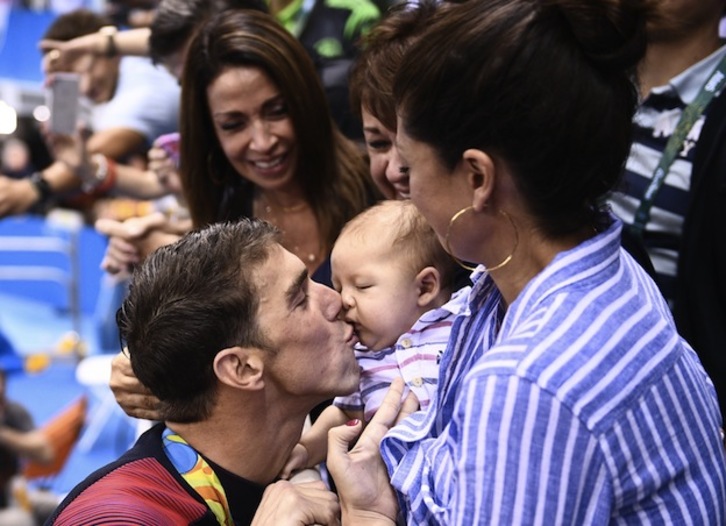 Michael Phelps besa a su hijo Boomer tras haber recibido una nueva medalla de oro. (Martin BUREAU / AFP)