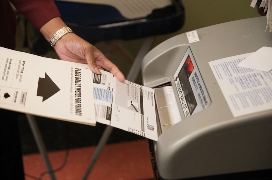 Una mujer introduce su papeleta de voto en el escáner. (Tasos KATOPODIS / AFP)