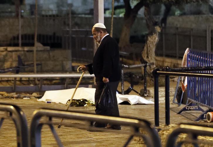Un hombre pasea por delante de un cadáver en Jerusalén. (Ahmad GHARABLI/AFP)