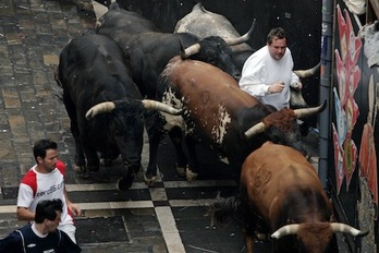 Los toros toman la curva de Estafeta con un mozo en el centro de la manada en un encierro del año pasado. (Iñigo URIZ/ARGAZKI PRESS)
