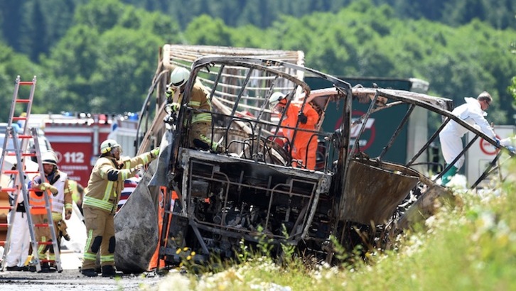 Los bomberos trabajan en el lugar del accidente, con el autobús totalmente calcinado. (Christof STACHE/AFP) 