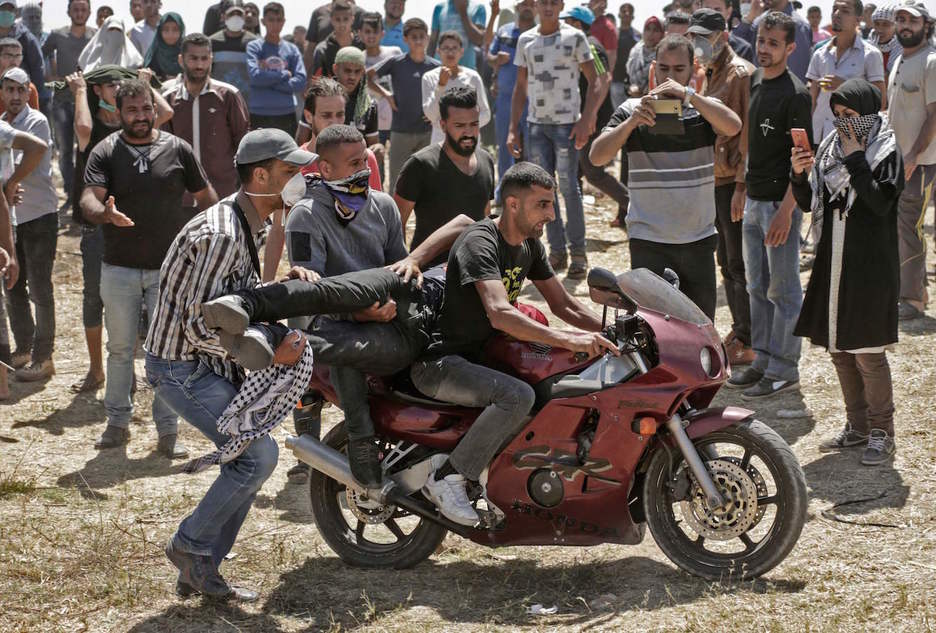 Dos jóvenes trasladan en moto a uno de los palestinos heridos. (Mahmud HAMS / AFP)