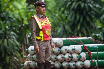 Un oficial de la Policía tailandesa, junto a unas bombonas de oxígeno. (YE AUNG THU/AFP)