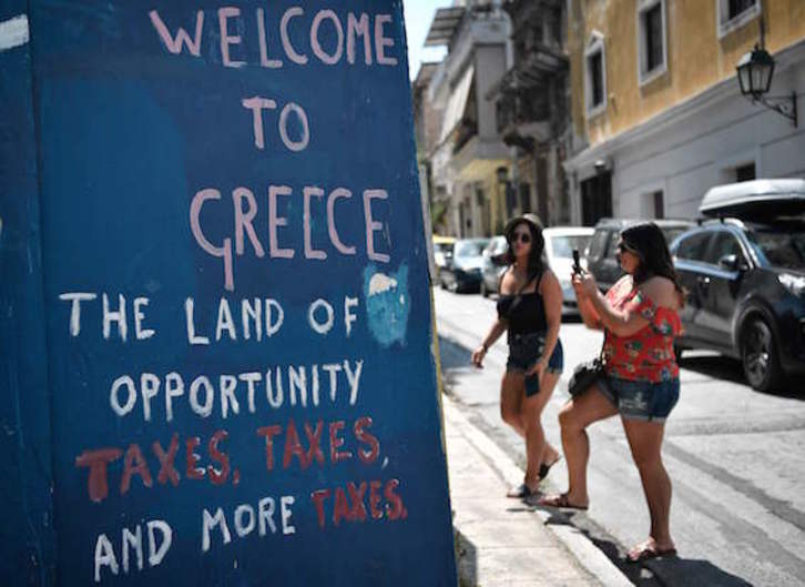Bi turista, Atenaseko hormetako margoketei argazkiak ateratzen. (Louisa GOULIAMAKI/AFP)