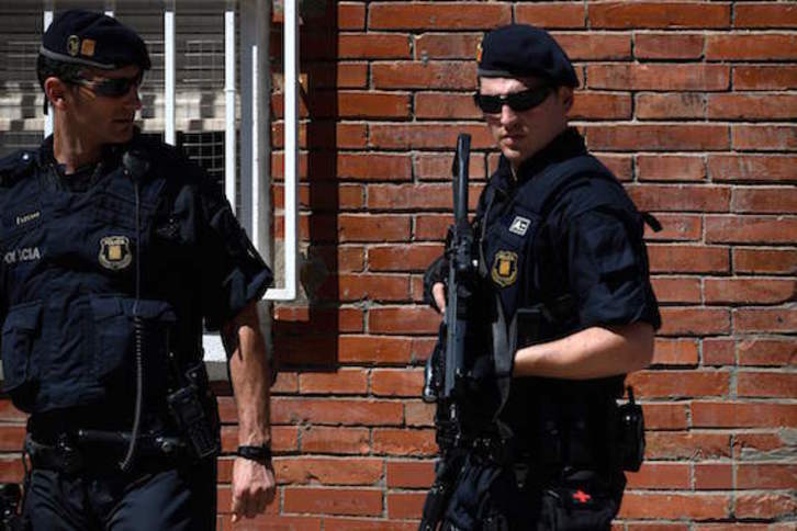 Dos agentes de los Mossos d'Esquadra, durante el registro de la vivienda del fallecido. (Lluís GENÉ/AFP)