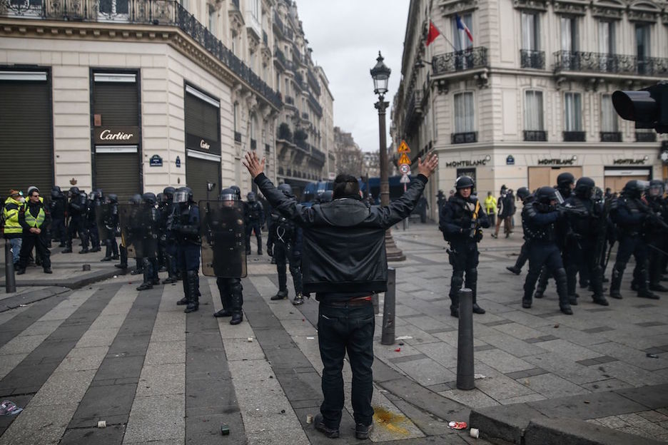 Un hombre alza los brazos ante la nutrida presencia policial.  (ABDUL ABEISSA / AFP)
