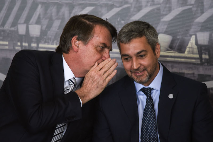 Bolsonaro susurra al oído de su homólogo paraguayo, Mario Abdo Benítez, durante la toma de posesión del nuevo director de la parte brasileña de Itaipú. (Norberto DUARTE/AFP)
