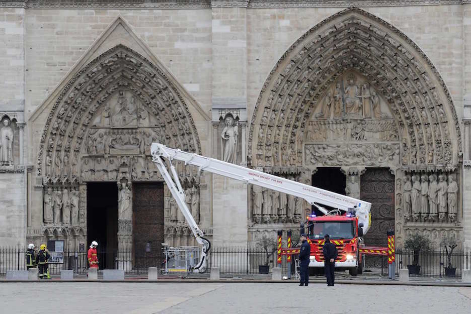 Los bomberos, ante la entrada principal de la catedral. (Thomas SAMSON / AFP)