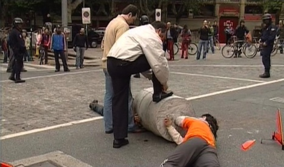 Simón Santamaría, jefe de la Policía Municipal de Iruñea, se ata los cordones sobre el bidón al que están encadenados dos miembros del movimiento okupa Piztera! en mayo de 2007. (Taburete Taldea)