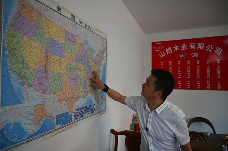 El fundador de la empresa china San Wood, ubicada en Shanghai, muestra a qué lugares de EEUU exportan maderas. (Hector RETAMAL / AFP).