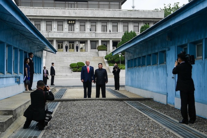 Trump –pisando territorio norcoreano– y Kim Jong-un posan juntos ante la línea de demarcación en un anterior encuentro. (Brendan SMIALOWSKI | AFP)