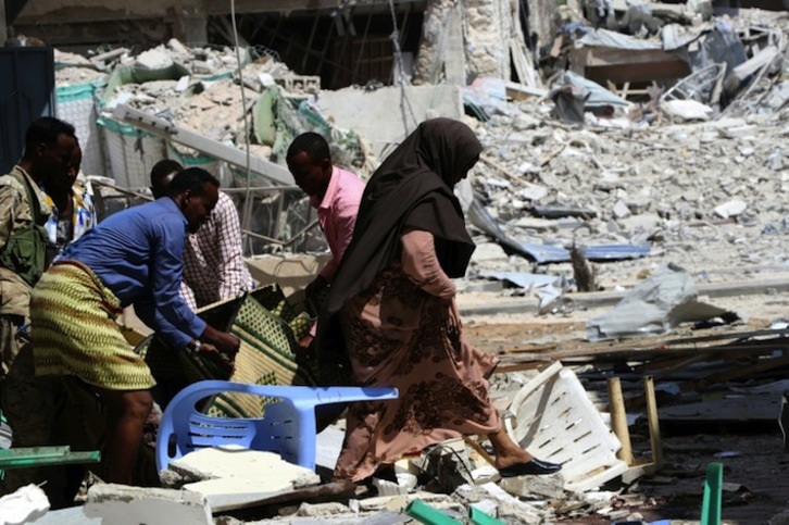 Varias personas evacúan un cuerpo tras un atentado contra un hotel de Mogadiscio el pasado 1 de marzo. (Abdirazik HUSSEIN FARAH /AFP)