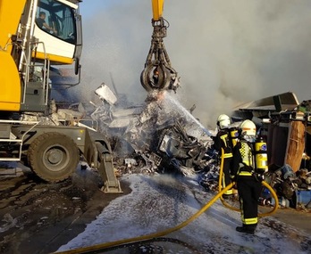 Personal de la chatarrería retira el material que ardía mientras los bomberos lanzan agua para apagarlo. (GOBIERNO DE NAFARROA)