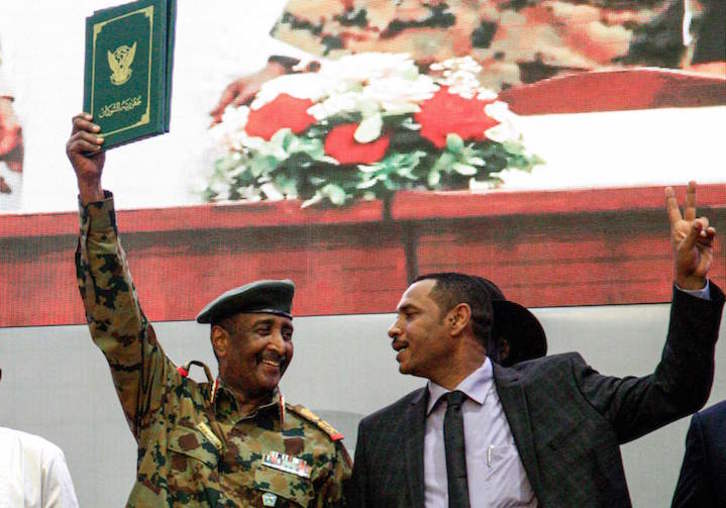 El jefe de la junta militar, Abdelfatah al Burhan, levanta el acuerdo constitucional, junto al líder opositor Ahmad Rabie. (Ebrahim HAMID/AFP)