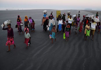 Refugiados rohingya caminan sobre la playa de Saplapur tras huir a Bangladesh por mar en noviembre de 2017. (Dibyangshu SARKAR/AFP)