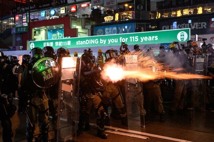 Policías lanzando gases lacrimógenos a manifestantes. (Phillip FONG / AFP).