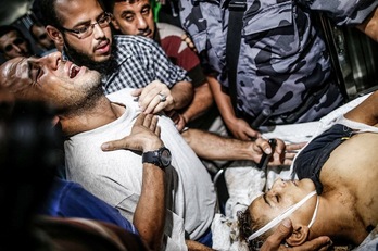 El padre de uno de los jovénes palestinos muertos por soldados israelíes lloran junto al cadáver de su hijo. (Mahmud HAMS / AFP)