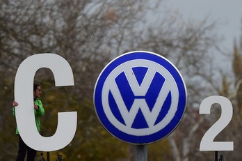 Un activista de Greenpeace sostiene carteles junto al logo de VW para protestar en contra de las emisiones de CO2.(John MACDOUGALL / AFP)